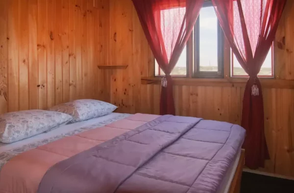Cabaña Familiar. Se ve el dormitorio principal con una cama matrimonial. La cama está preparada con ropa de cama comfortable.