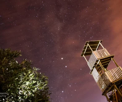 Cielo nocturno con estrellas y galaxias. Se ve la torre mirador de Ocho Águilas Eco Lodge.